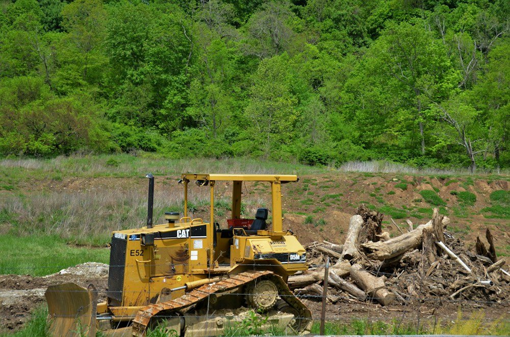 A mini excavator pulling stumps and brush on a partly cleared wooded lot